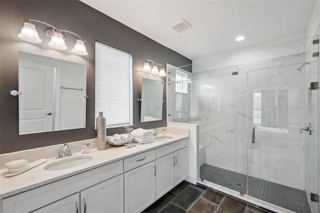 full bath featuring double vanity, a stall shower, visible vents, and a sink