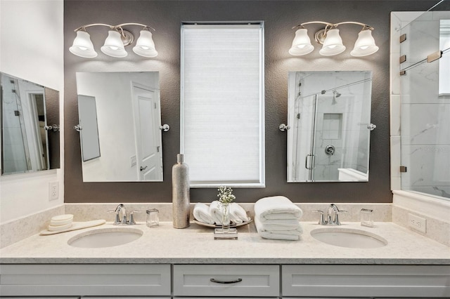 bathroom with a sink, a shower stall, and double vanity