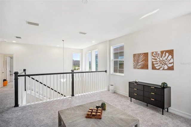 living area featuring visible vents, carpet, an upstairs landing, and baseboards