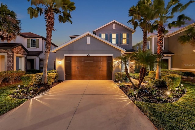 view of front of house with a garage, concrete driveway, and stucco siding