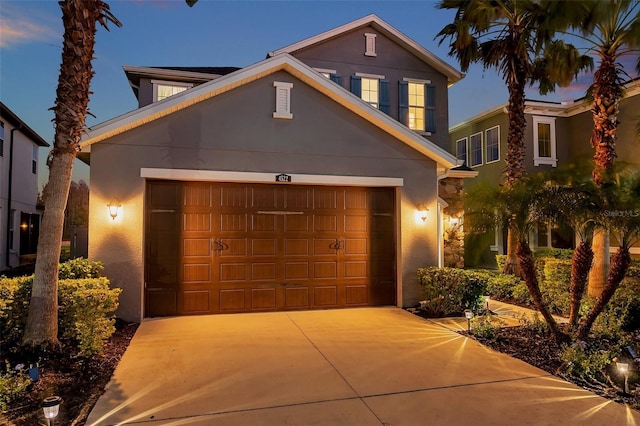 traditional-style house with a garage, driveway, and stucco siding