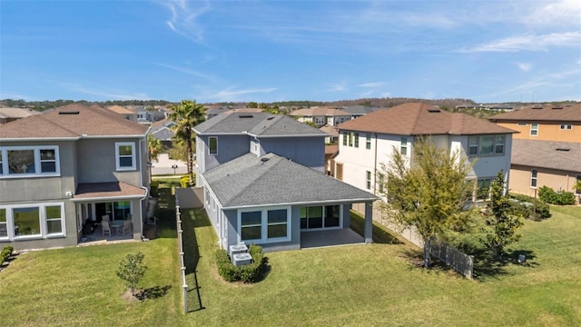 rear view of property featuring a residential view, a patio area, and a lawn