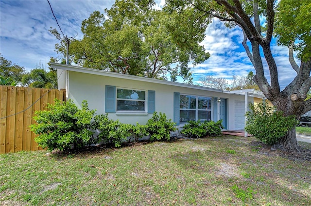 view of front of home with a garage, a front yard, fence, and stucco siding