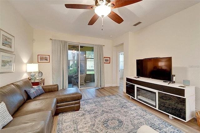 living area with a ceiling fan, baseboards, visible vents, and light wood finished floors