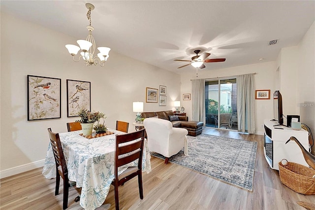 dining room featuring visible vents, ceiling fan with notable chandelier, light wood-type flooring, and baseboards