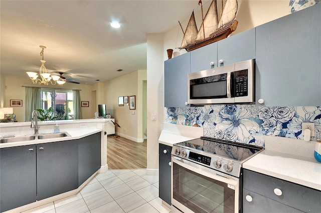 kitchen with light countertops, decorative backsplash, gray cabinets, appliances with stainless steel finishes, and a sink