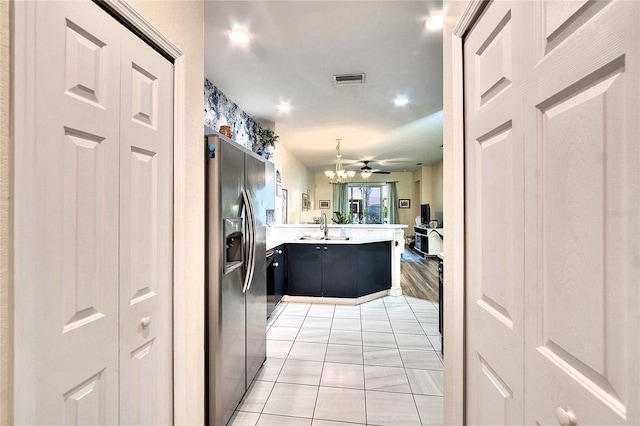 kitchen featuring stainless steel refrigerator with ice dispenser, a sink, open floor plan, a peninsula, and light countertops