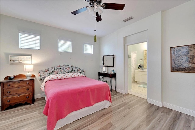 bedroom featuring connected bathroom, visible vents, baseboards, and wood finished floors