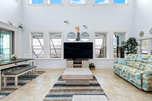 living area with stone finish floor, baseboards, and a towering ceiling