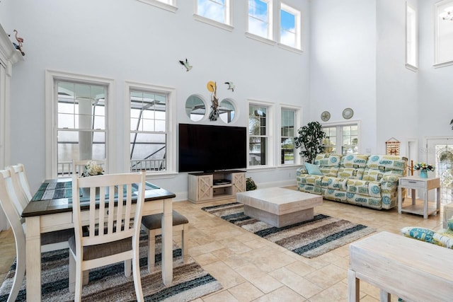 living room featuring baseboards, plenty of natural light, a notable chandelier, and a towering ceiling