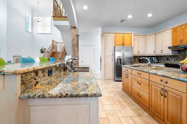 kitchen featuring tasteful backsplash, light stone counters, stainless steel fridge, and a sink