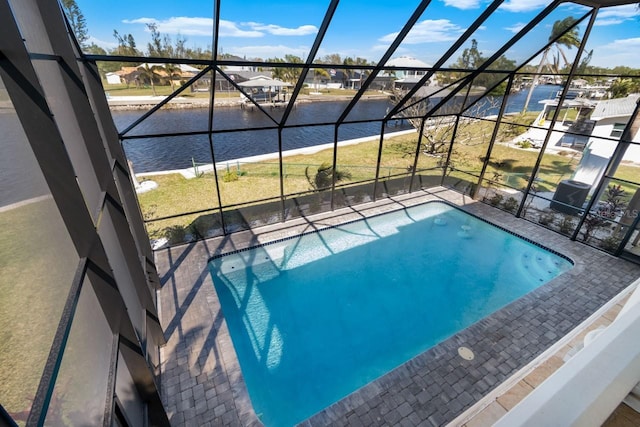 view of swimming pool featuring glass enclosure and a water view