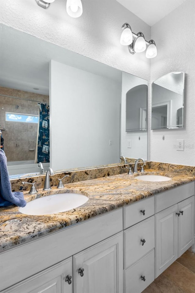 full bathroom featuring double vanity, tile patterned flooring, and a sink