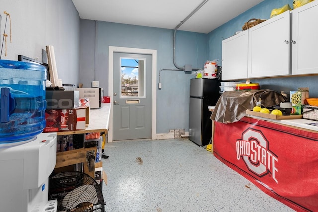 interior space featuring speckled floor, white cabinetry, freestanding refrigerator, and light countertops