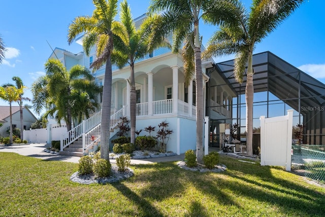 view of front of house with a lanai, a front lawn, and fence