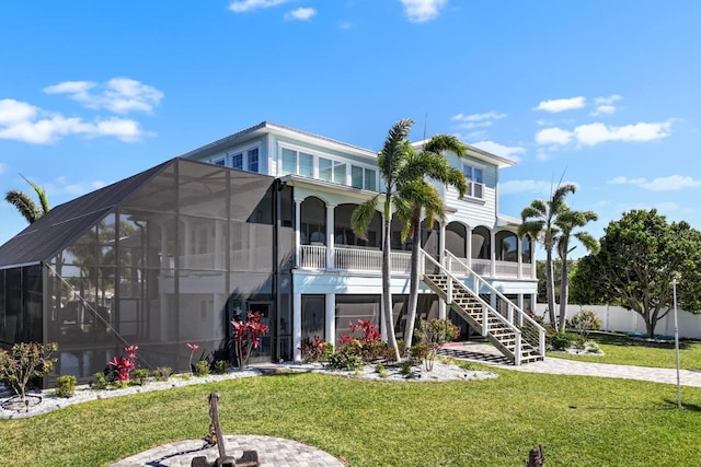 rear view of property featuring stairway, a lawn, glass enclosure, and fence