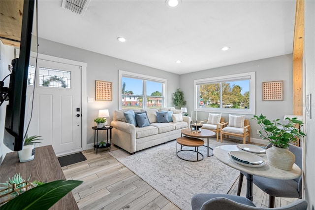 living room with light wood-style floors, a wealth of natural light, visible vents, and recessed lighting