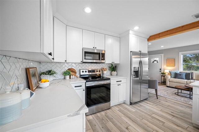 kitchen featuring white cabinets, light wood-style floors, appliances with stainless steel finishes, and decorative backsplash