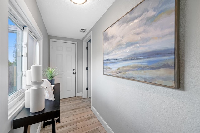 corridor featuring light wood-style floors, visible vents, and baseboards