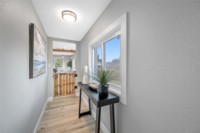 doorway with a textured wall and light wood-style flooring