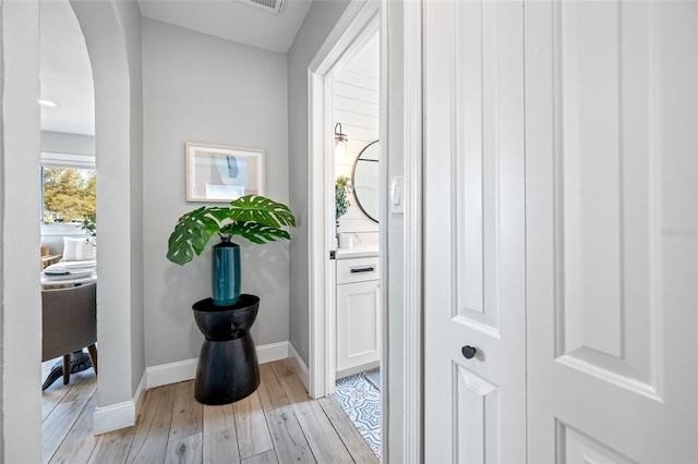 interior space featuring light wood-style floors, arched walkways, and baseboards