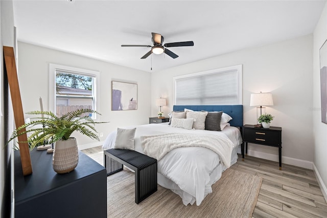 bedroom with a ceiling fan, light wood-style flooring, and baseboards