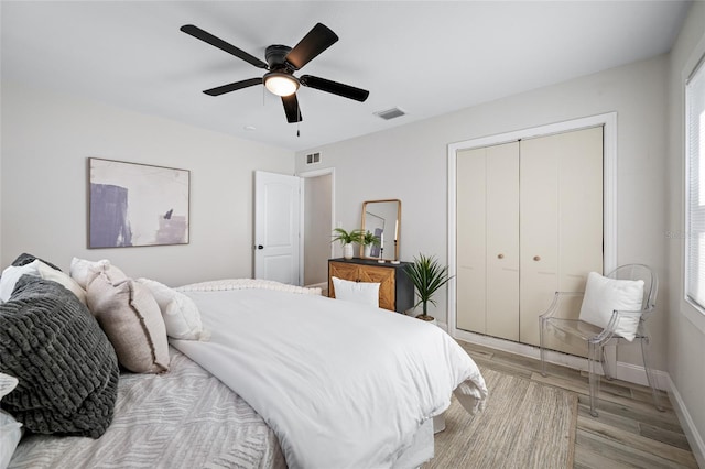 bedroom featuring light wood-type flooring, baseboards, visible vents, and a closet