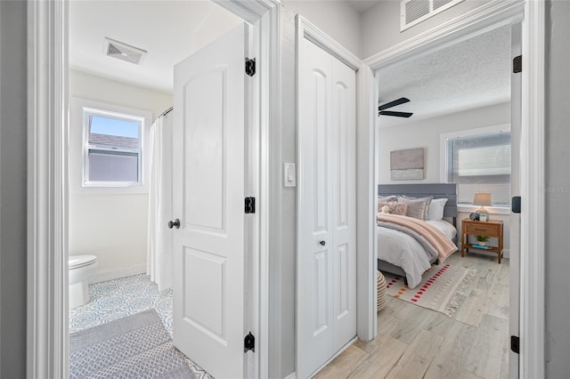 hallway featuring light wood-style floors, visible vents, and baseboards