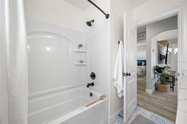 bathroom with connected bathroom, wood finished floors, visible vents, baseboards, and shower / bath combo