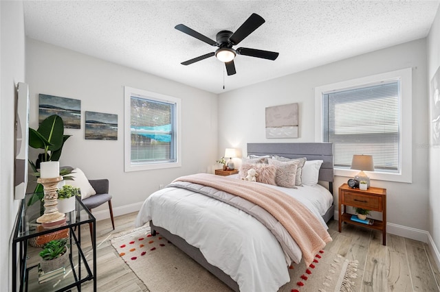 bedroom with a textured ceiling, light wood finished floors, a ceiling fan, and baseboards