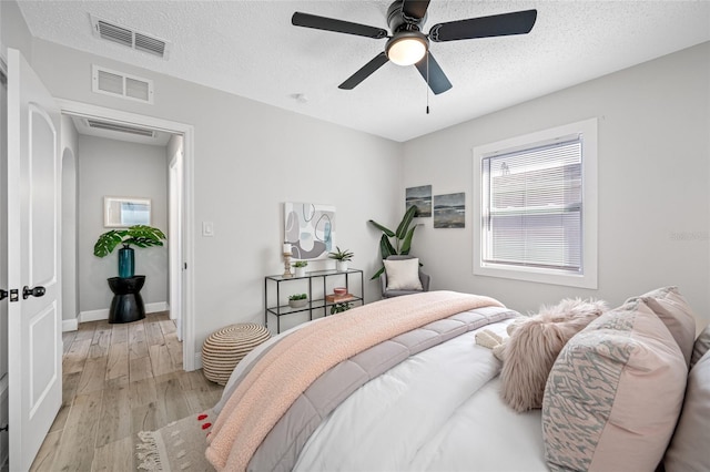 bedroom with light wood-type flooring, visible vents, and a textured ceiling