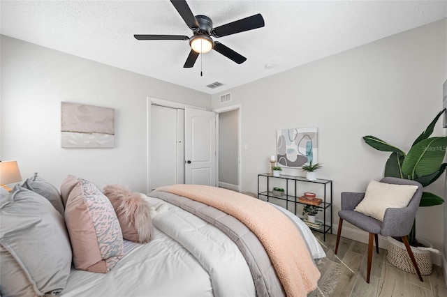 bedroom with light wood finished floors, a closet, visible vents, and a ceiling fan