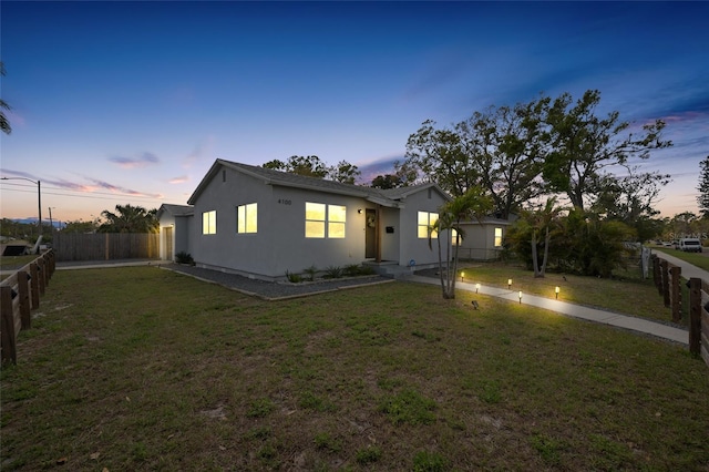 view of front facade with a front yard, fence, and stucco siding