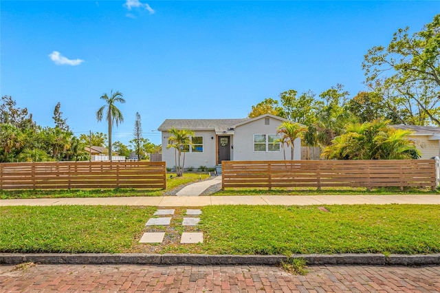 view of front facade featuring a fenced front yard, a front yard, and stucco siding