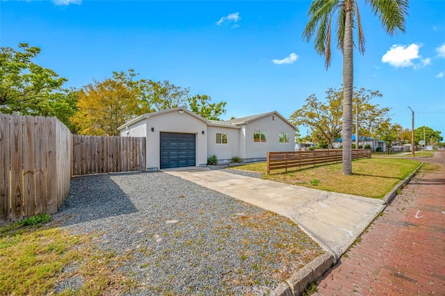 view of front of house featuring driveway, an attached garage, fence, a front lawn, and stucco siding