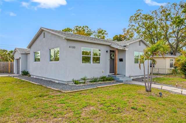 single story home featuring a garage, fence, a front lawn, and stucco siding