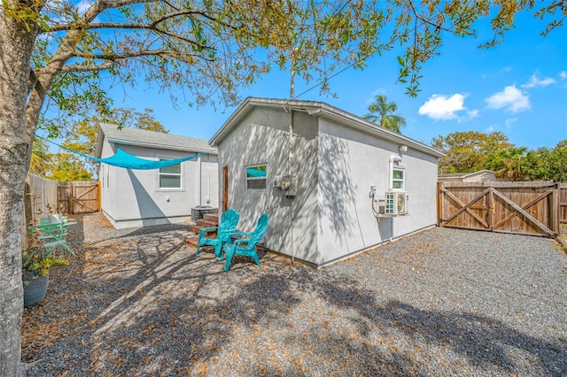 back of property featuring cooling unit, a gate, fence, and stucco siding