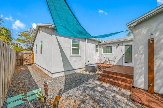 back of property with a fenced backyard, cooling unit, a wooden deck, and stucco siding