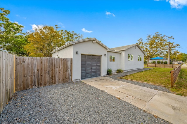 view of front facade with driveway, an attached garage, fence, a front lawn, and stucco siding