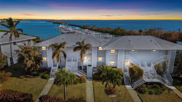 view of property featuring a water view, stairway, and metal roof