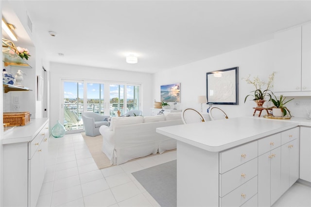 kitchen featuring light tile patterned floors, a peninsula, white cabinetry, open floor plan, and light countertops