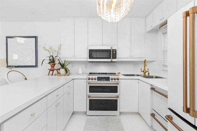 kitchen featuring white appliances, light countertops, a sink, and white cabinetry