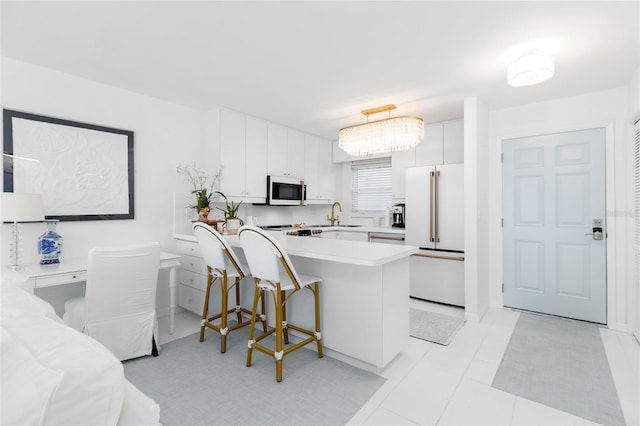 kitchen with light countertops, white cabinets, a sink, white appliances, and a peninsula