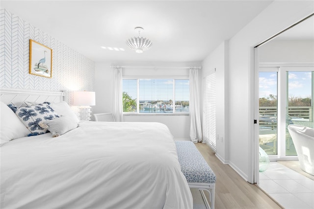 bedroom featuring an accent wall, access to outside, multiple windows, and wallpapered walls