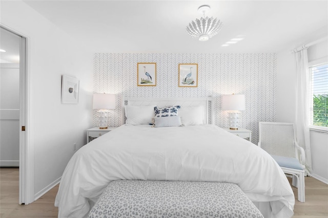 bedroom featuring wallpapered walls, an accent wall, and baseboards