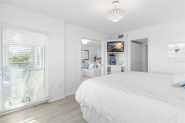 bedroom featuring light wood-style flooring, a notable chandelier, visible vents, baseboards, and ensuite bath