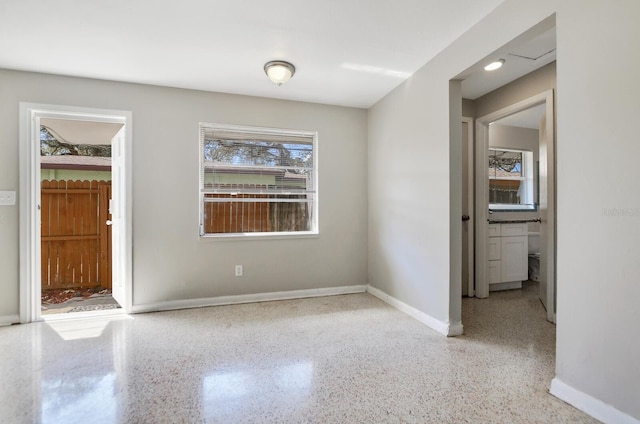 unfurnished room featuring baseboards and speckled floor