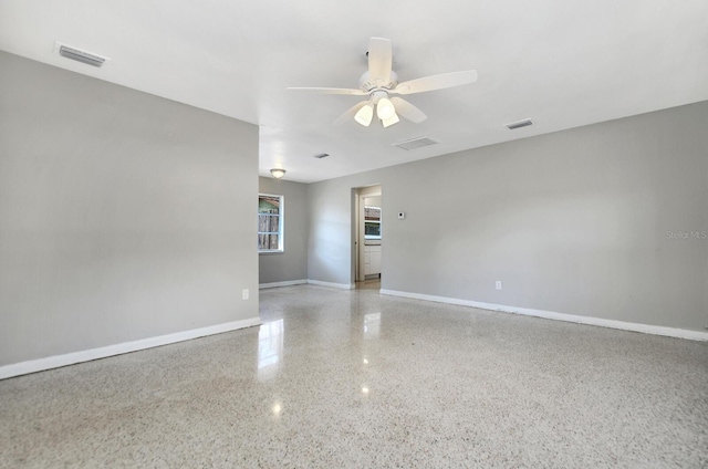 empty room featuring visible vents, ceiling fan, baseboards, and speckled floor