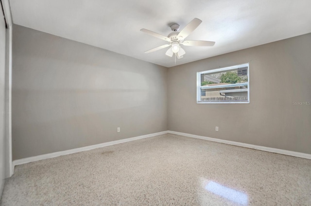 unfurnished room with ceiling fan, speckled floor, and baseboards