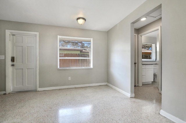 unfurnished room with baseboards and speckled floor